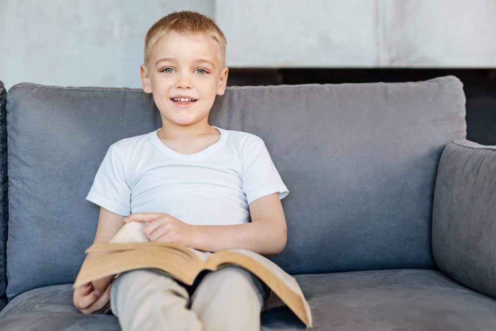 A child in foster care reading a book on the couch