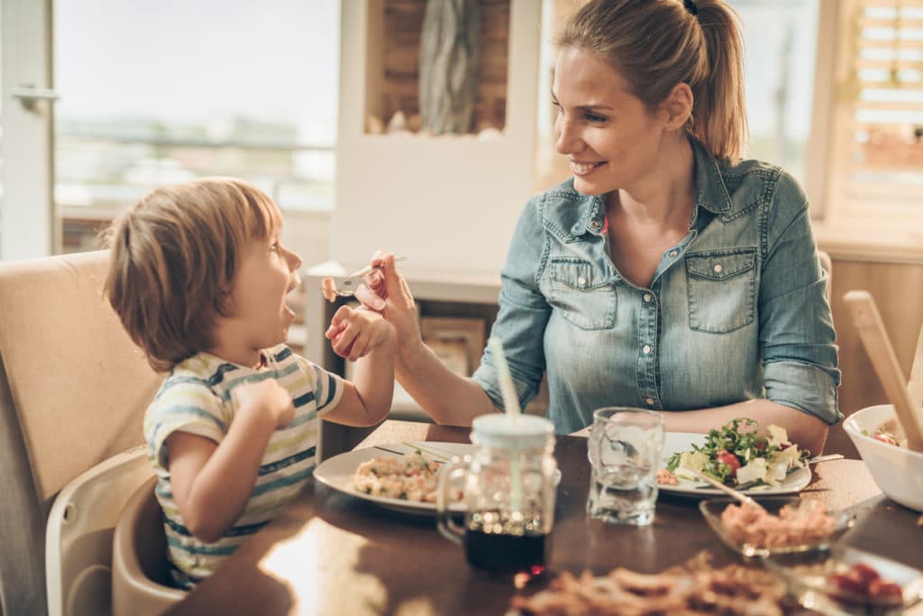 mother feeding foster child at table with food from support group